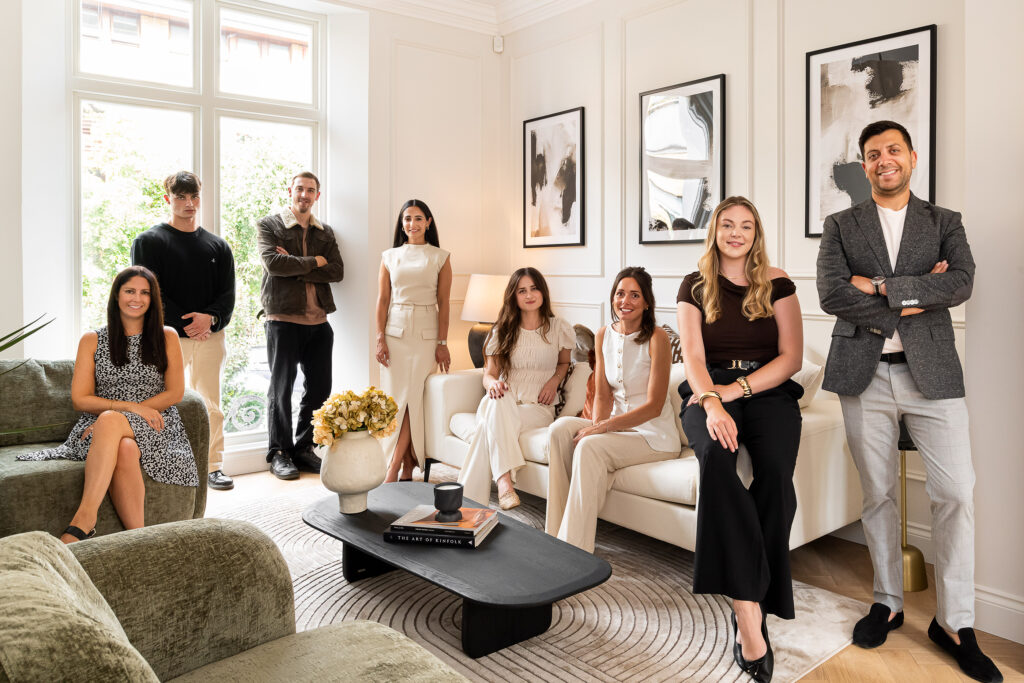 team photo for LJ Interiors with 8 people in the frame. neutral decor with black coffee table