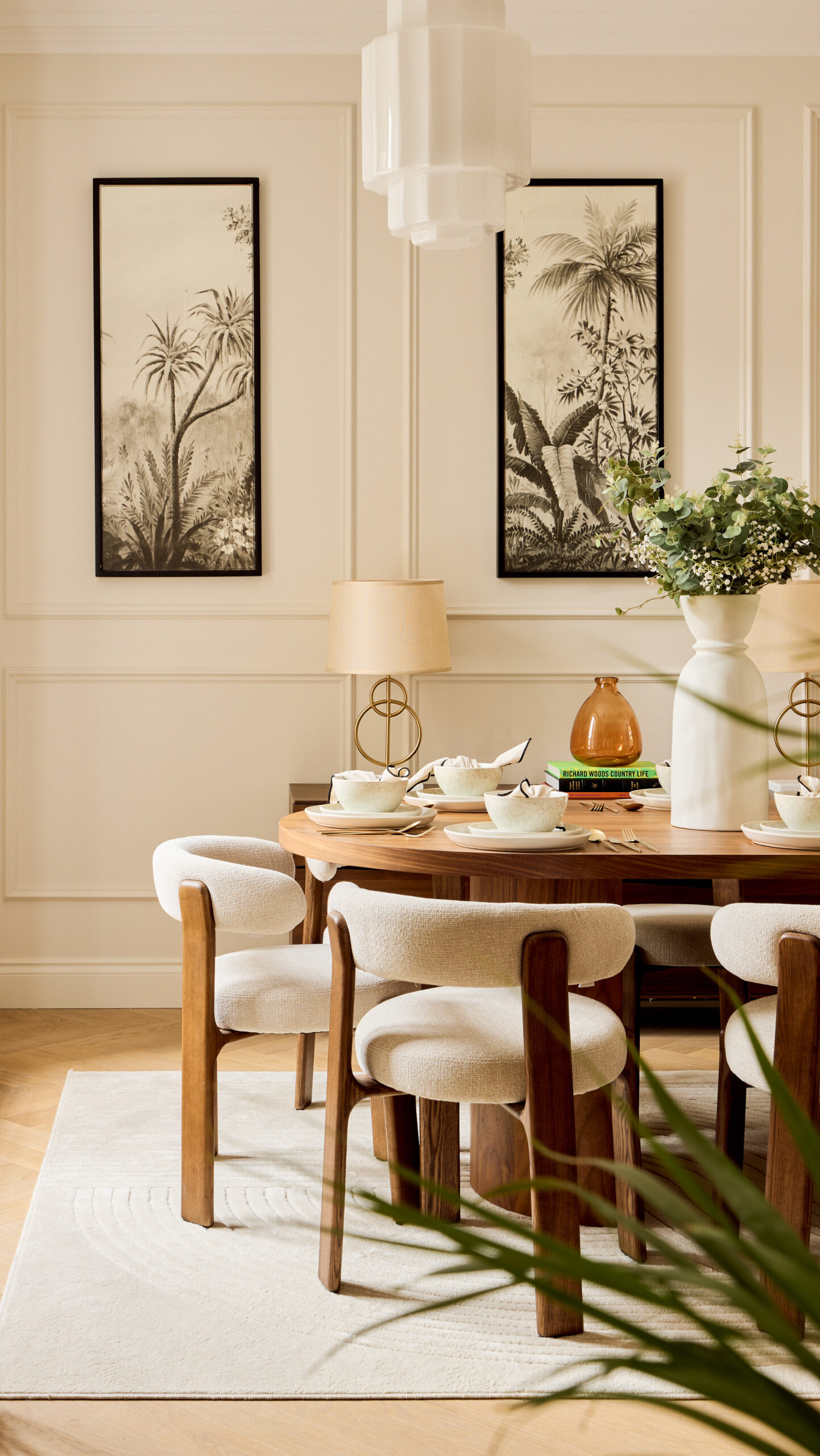 neutral interior dining room with large wooden table, beige boucle chairs, floral details and two artworks on wall