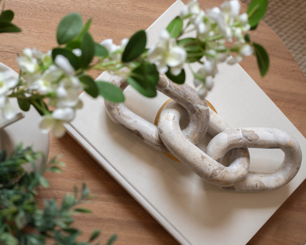 Close-up of marble-look chain ornament resting on a design book on a wooden tabletop.
