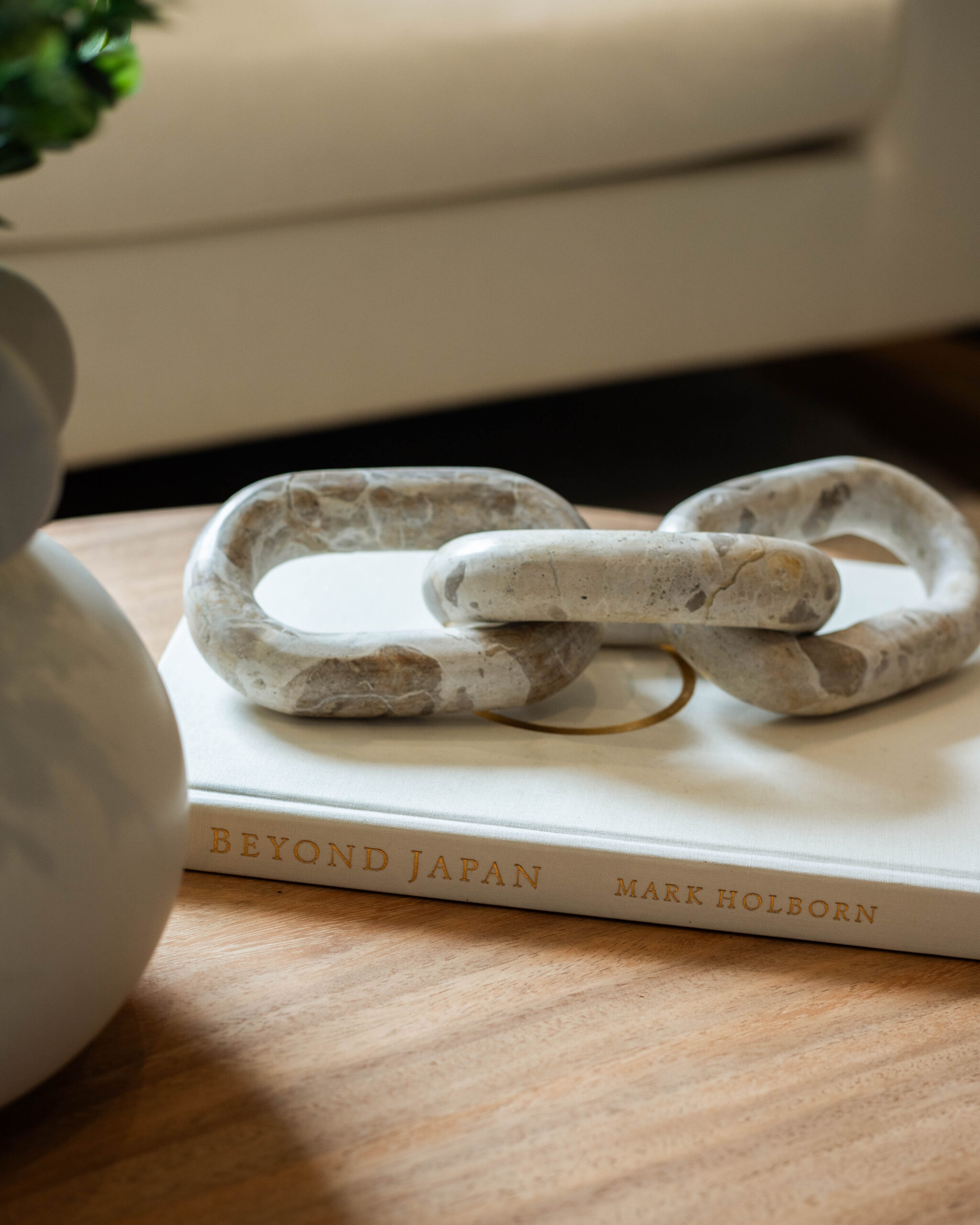 Close-up of marble-look chain ornament resting on a design book on a wooden tabletop.
