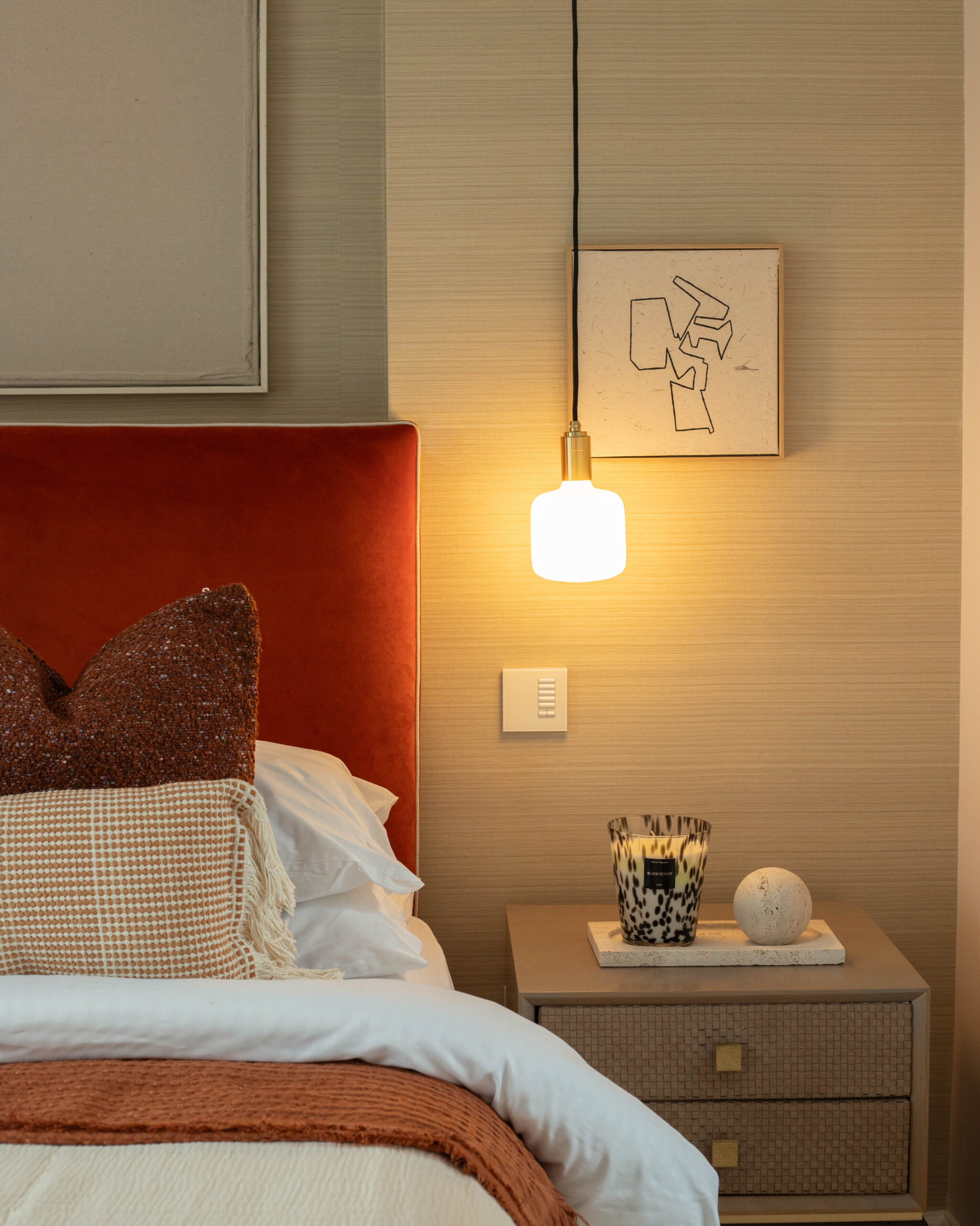Home staging bedroom featuring warm autumnal tones, textured cushions, and one ambient pendant light