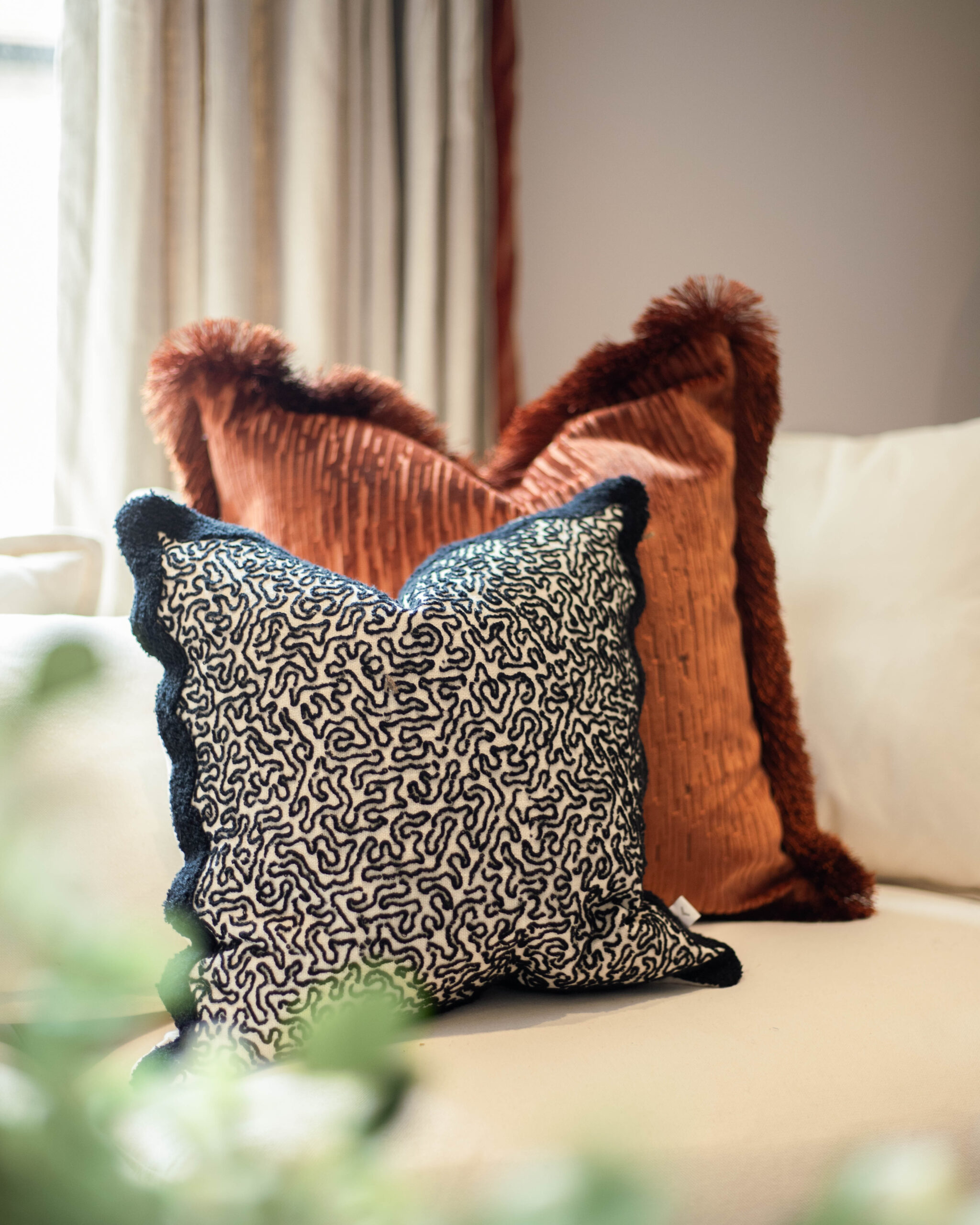 one rust cushion and one black white patterned cushion on a cream sofa