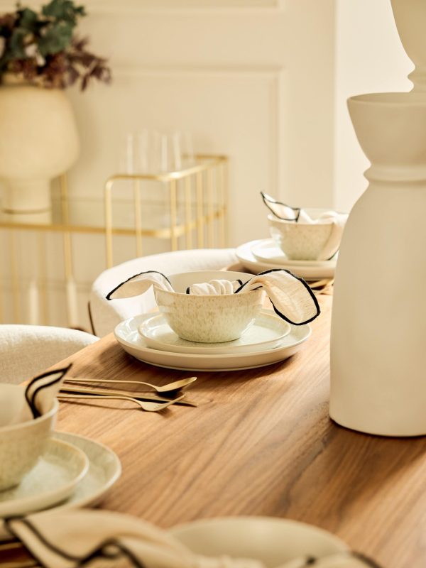 Styled dining wood table with neutral accessories and cream white plate and bowls